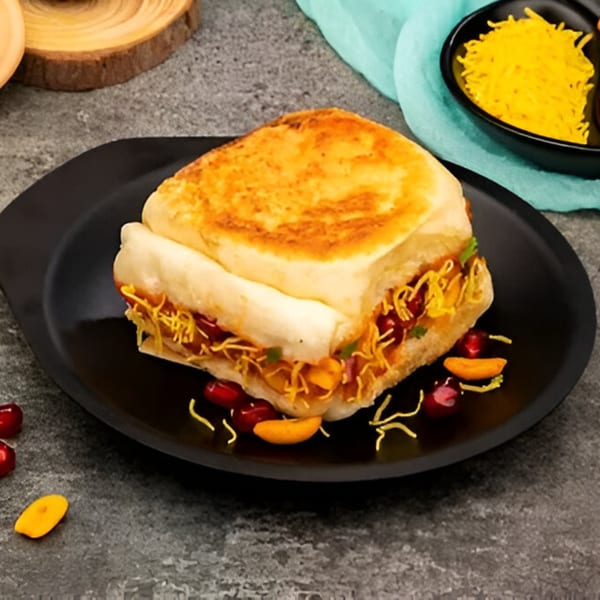 A Turmerica Indian sandwich with crispy noodles and red beans on a black plate.