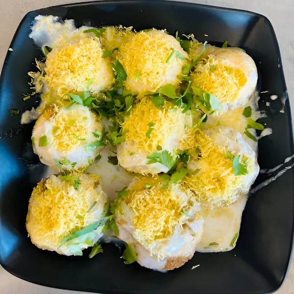 Turmerica's Indian dish features eight white dumplings topped with yellow crispy noodles and fresh cilantro.